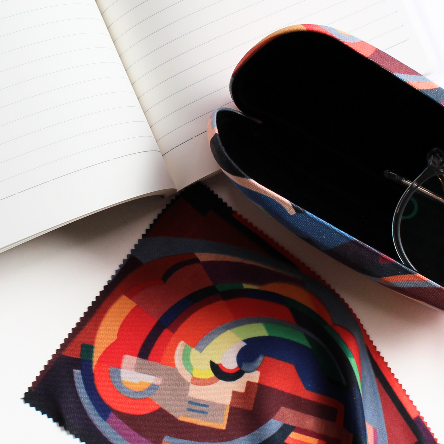 Open Notebook, glasses case and lens cloth all featuring A Composition by Mainie Jellett on a white background, with a pair of glasses in the open glasses case