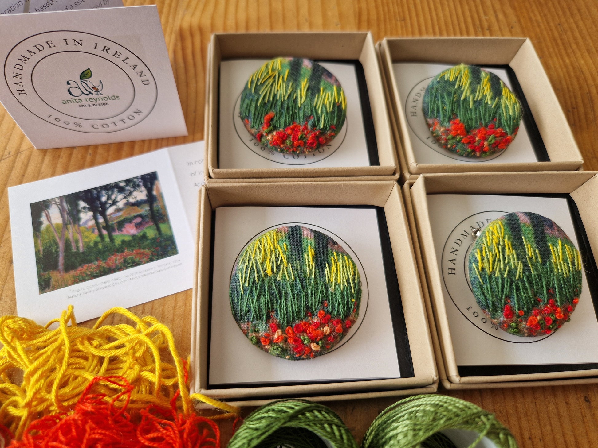Finished Anita Reynolds brooches in their boxes alongside the threads used to embroider them