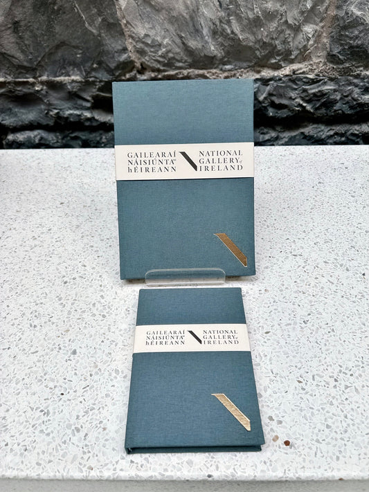 Two grey NGI and Duffy bookbinders notebooks with a National Gallery of Ireland label on a stone surface