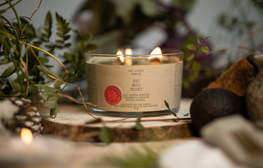 A three wick candle with each wick lit sitting on a tree stump display