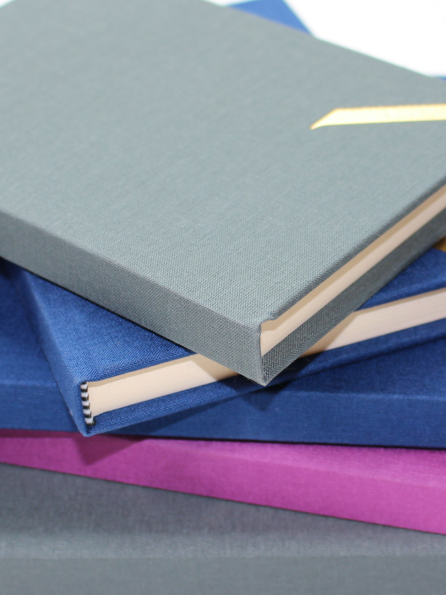 Stack of National Gallery and Duffy Bookbinders A5 Notebooks in Purple, Blue and Grey, showing the embossed gallery logo, cloth covers and the striped binding tape