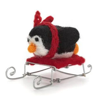 A handcrafted black penguin on a red and silver wire sledge, made from wool felt.