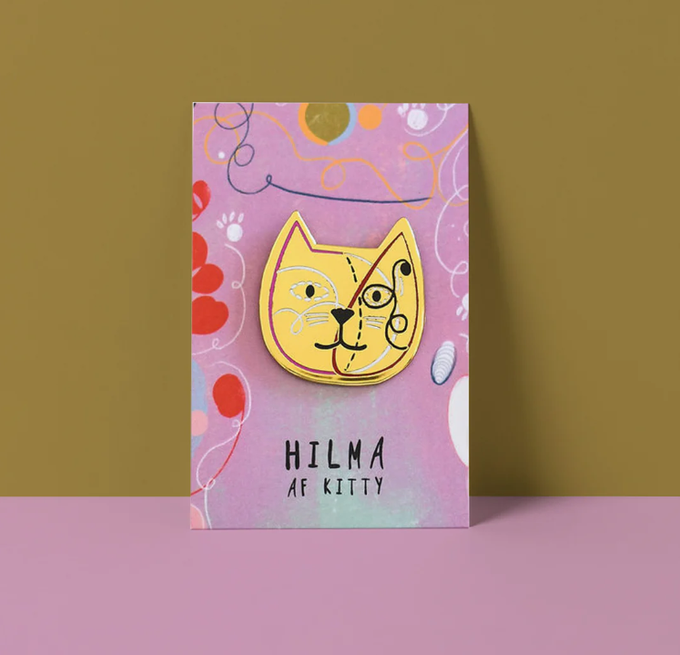 Cat-shaped brooch on a colorful card with 'HILMA AF KITTY' text against a green background.