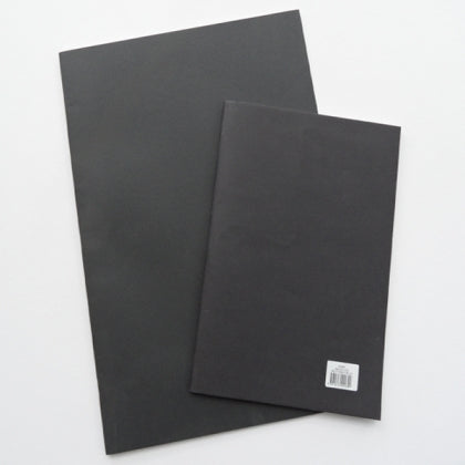 A plain black notebook cover. A small white sticker in the corner has the barcode and paper details.