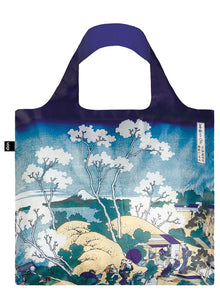 A square bag covered in a flat illustration of white trees with yellow hills. There a people in a small village to the left, and a snow topped mountain in the far background against a blue sky. The handle lining is a matching blue.