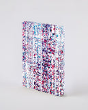 A notebook covered in a streaming pattern of small pink, purple and blue rectangles, that continues onto the paper edges.