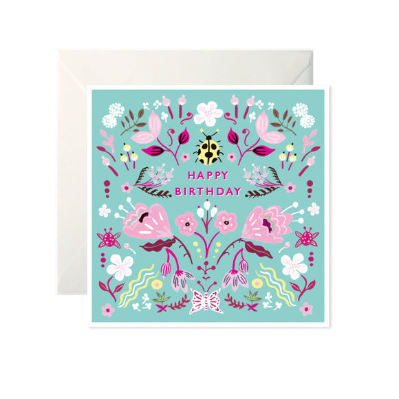 A turquoise card with drawings of flowers and insects in different shades of pink and some yellow. ‘Happy Birthday’ is written in pink capital letters with a yellow beetle above.