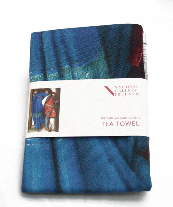 A folded tea towel with a grey label around the centre. The label shows a man in mail and a woman in blue stand on a castle staircase. The woman has her back to the viewer and her face turned from the man as they walk in opposite directions. He is embracing her arm as he descends.