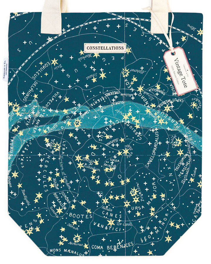 A tote bag with a celestial and star pattern, predominantly dark blue or black, with constellations labeled in white and yellow text.