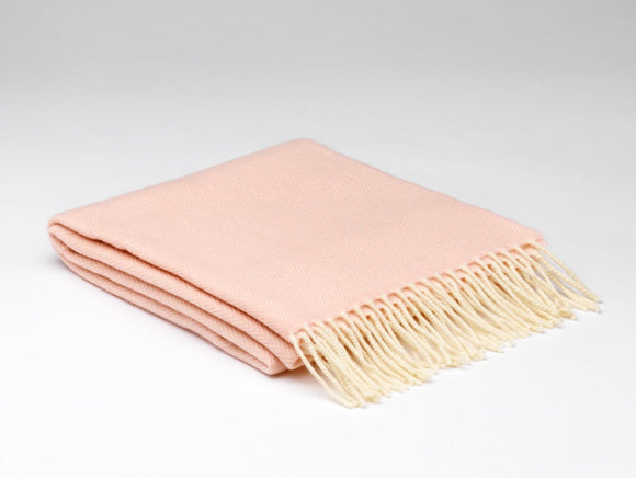A folded pale pink scarf with a subtle herringbone. There is a cream fringe on both ends.