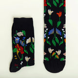 The socks flat showing how the pattern of flowers in blue, red, white, and pink with green leaves lays across the front.