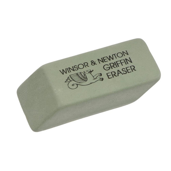 A muted sage green eraser, shaped like a rectangle with sloped sides. The name and logo are in black on top of the eraser.