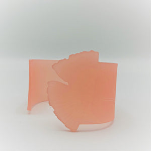 A pink cuff that is partially opened. One end is shaped like a ginkgo leaf with the designed etched into the bracelet.