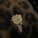 The bouquet of flowers pin on a coat. There multiple types of flowers with long stems tied together with a black bow.