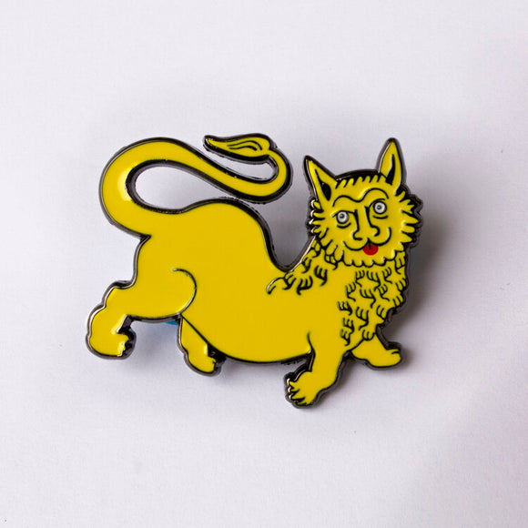 A yellow pin of a medieval style lion illustration which has a silly face, tongue sticking out, and no mane.