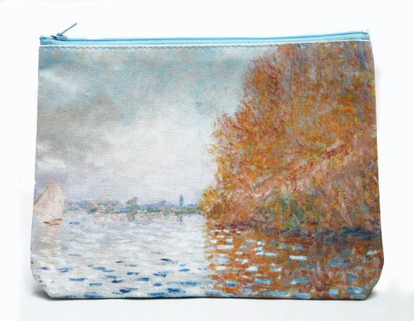 A zip top bag with an impressionist painting of a light blue sky and matching coloured lake. The right of the image is dominated by a large tree in autumn oranges which reflects into the water. On the left is a small boat with its white sail open.