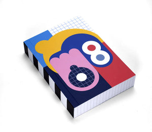 A thick notebook with a colourful pattern of shapes in pink, red, yellow, white, navy and blue. The pages are a grid.