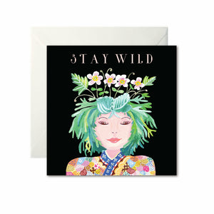 A black card with a drawing of a woman from the shoulders up. She has green hair with flowers growing from the top. ‘Stay Wild’ is written in white capital letters at the top.