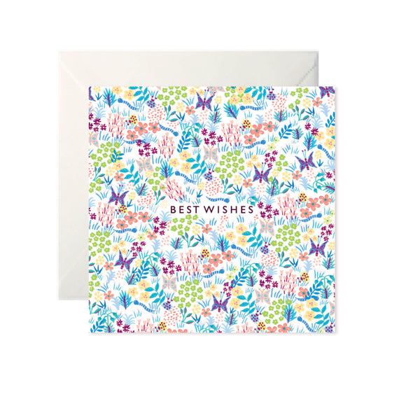 A white card with a drawn pattern of flowers and butterflies in bright colours. In the centre ‘Best Wishes’ is written in black capitals.