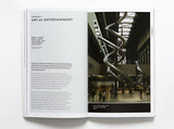 A two page spread from inside the book about art as entertainment. On the left page is text and on the right is a photo of a long, two storey high, twisting slide inside a building.