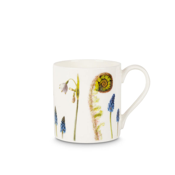 A white mug covered in paintings of flowers in different types and sizes, in blue, white and green.