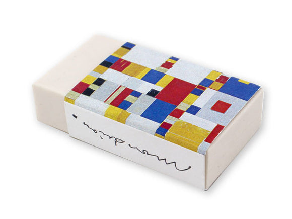 A white eraser in a card sleeve. The sleeve is covered in small of red, yellow, grey, white, black and blue squares in different sizes and patterns. A reproduction of Mondrian’s signature is on the side.